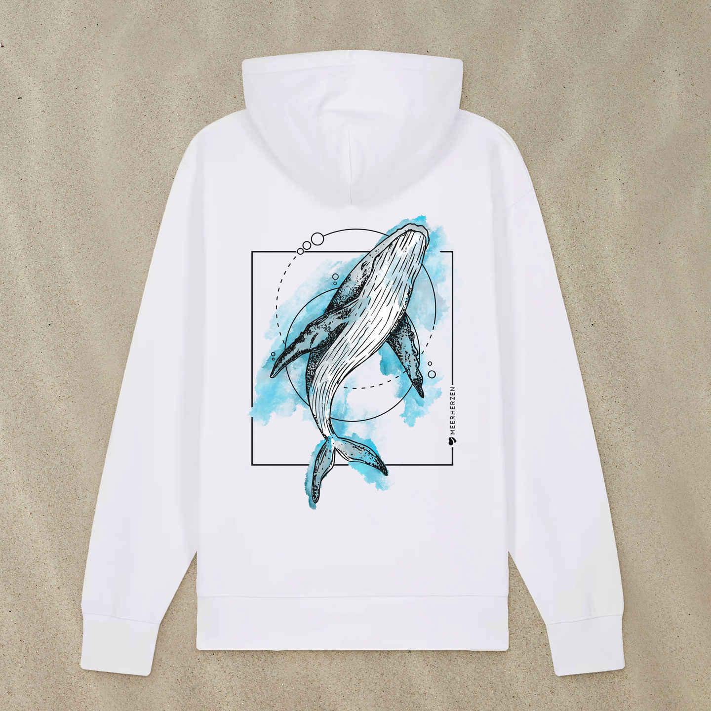 Weißer Hoodie mit Buckelwal-Motiv mit Aquarell-Farben liegt im Sand.