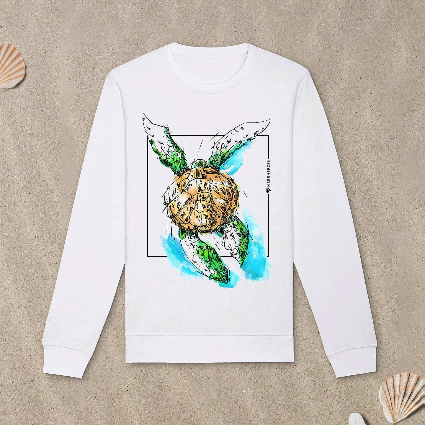 Weißes Sweatshirt mit Meeresschildkröte-Motiv mit Astrologie-Elementen liegt im Sand.