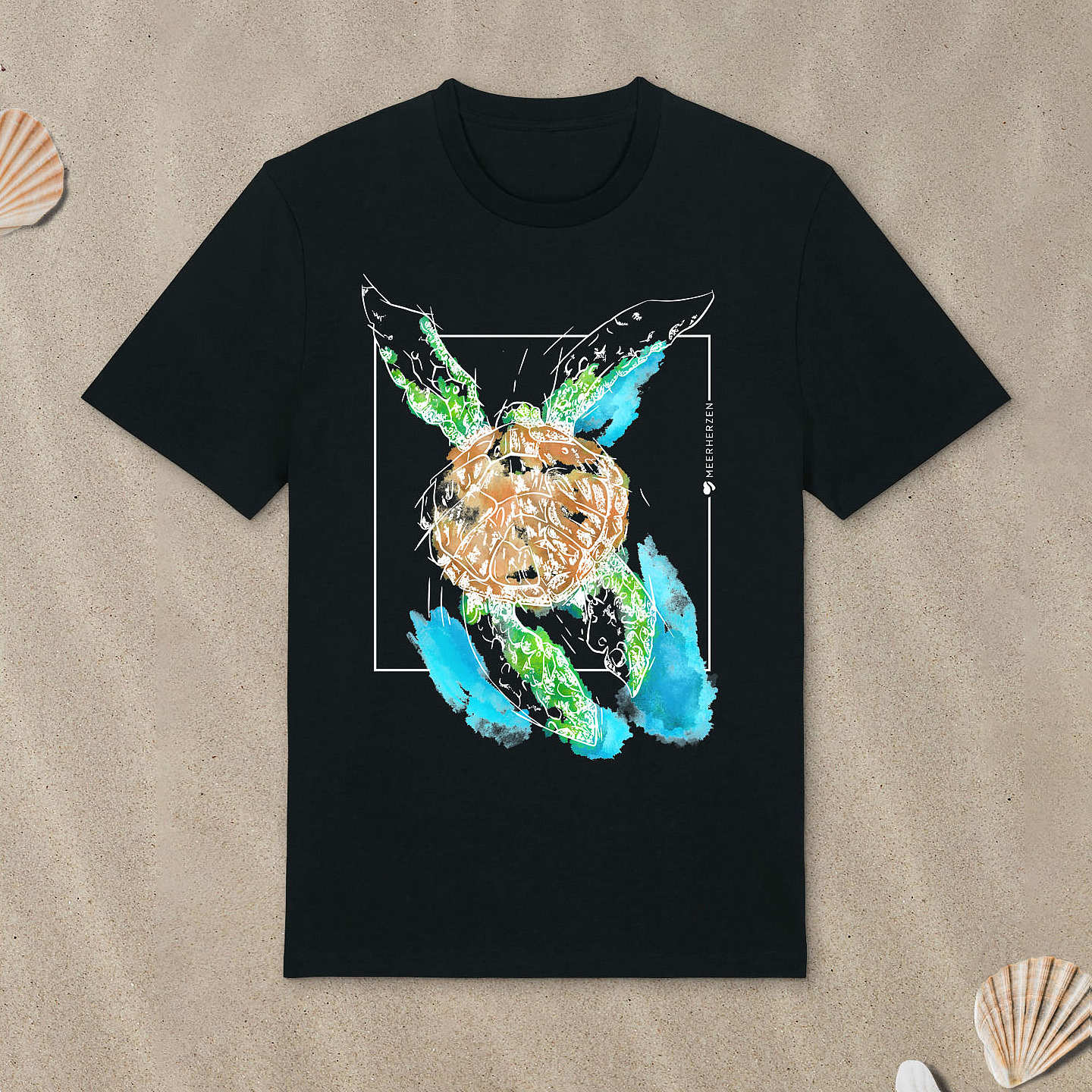Schwarzes T-Shirt mit Meeresschildkröte-Motiv mit bunten Aquarell-Farben liegt im Sand.
