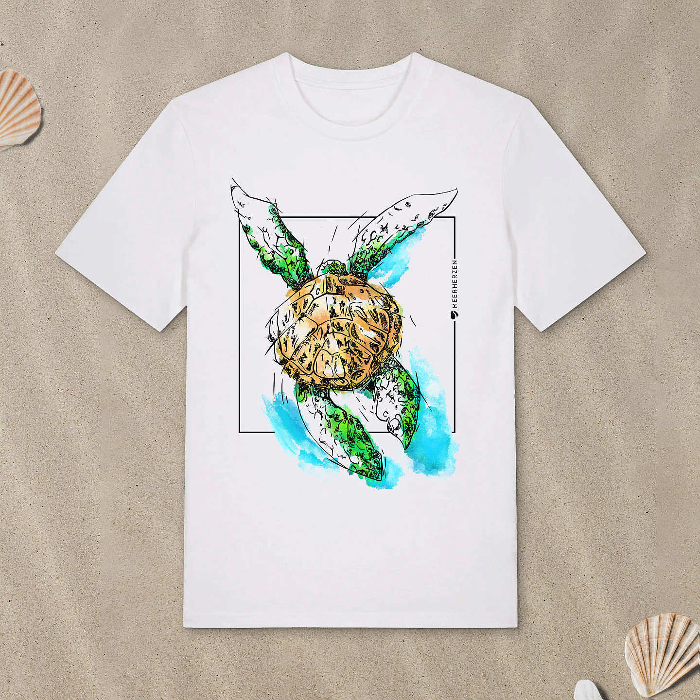 Weißes T-Shirt mit Meeresschildkröte-Motiv mit bunten Aquarell-Farben liegt im Sand.