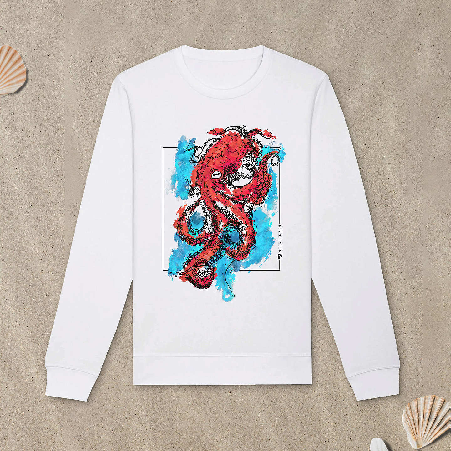 Weißes Sweatshirt mit Tintenfisch-Motiv mit bunten Aquarell-Farben liegt im Sand.