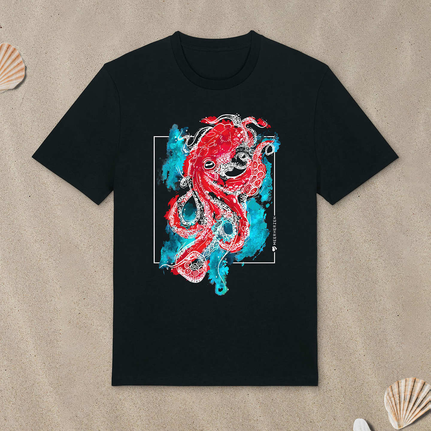Schwarzes T-Shirt mit Tintenfisch-Motiv mit bunten Aquarell-Farben liegt im Sand.