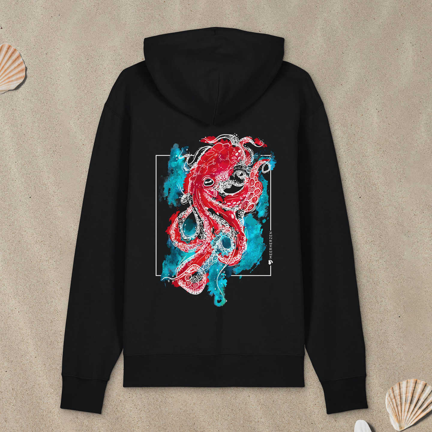 Schwarzer Hoodie Zipper mit Tintenfisch-Motiv mit bunten Aquarell-Farben liegt im Sand.
