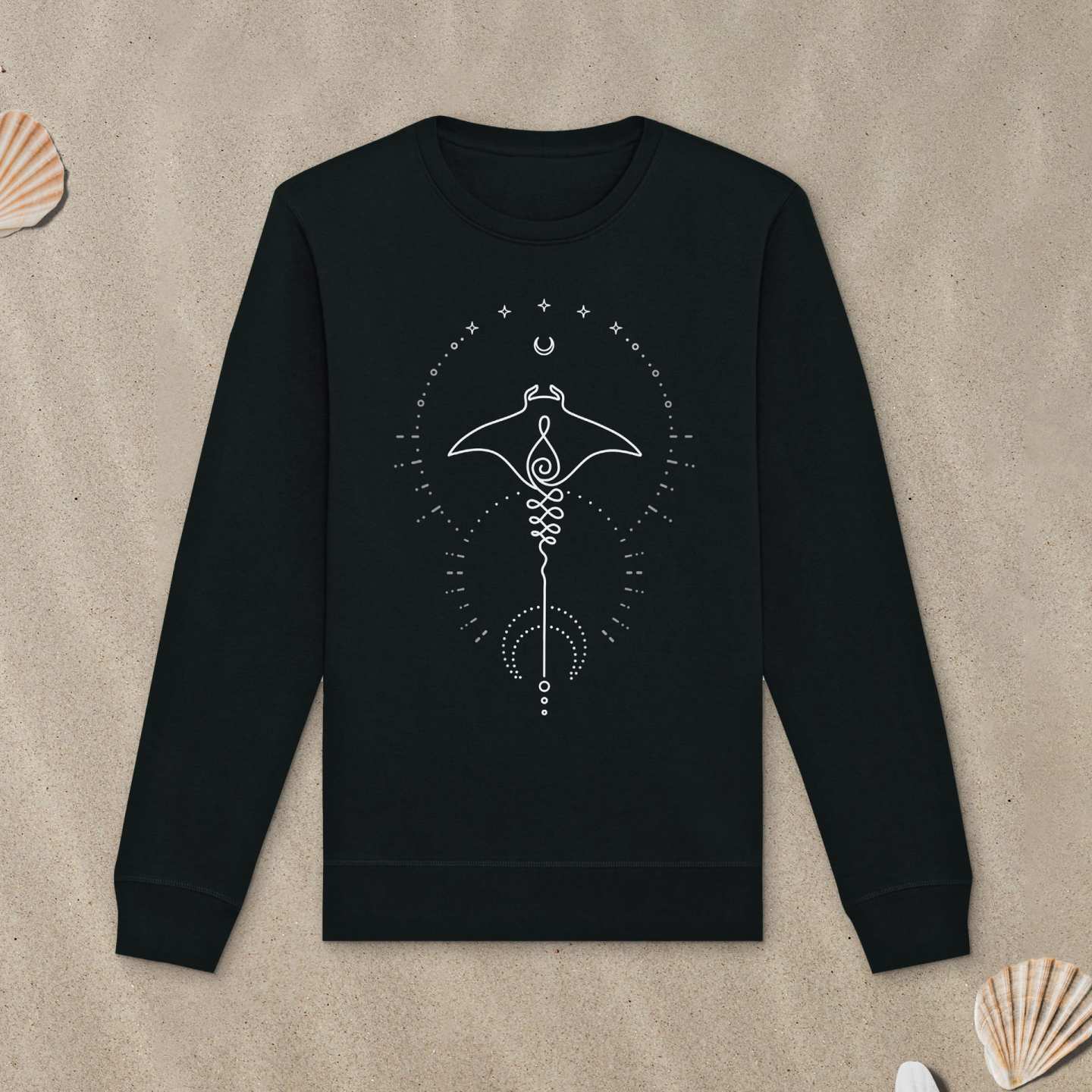 Schwarzes Sweatshirt mit Manta-Motiv mit Astrologie-Elementen liegt im Sand.