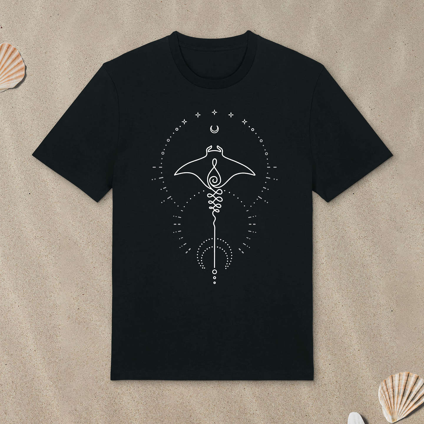 Schwarzes T-Shirt mit Manta-Motiv mit Astrologie-Elementen liegt im Sand.