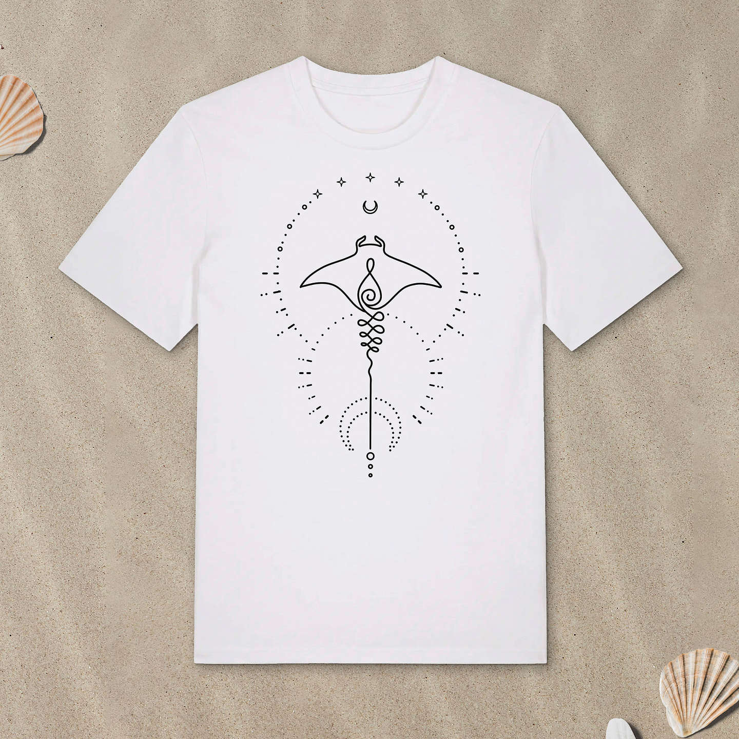 Weißes T-Shirt mit Manta-Motiv mit Astrologie-Elementen liegt im Sand.