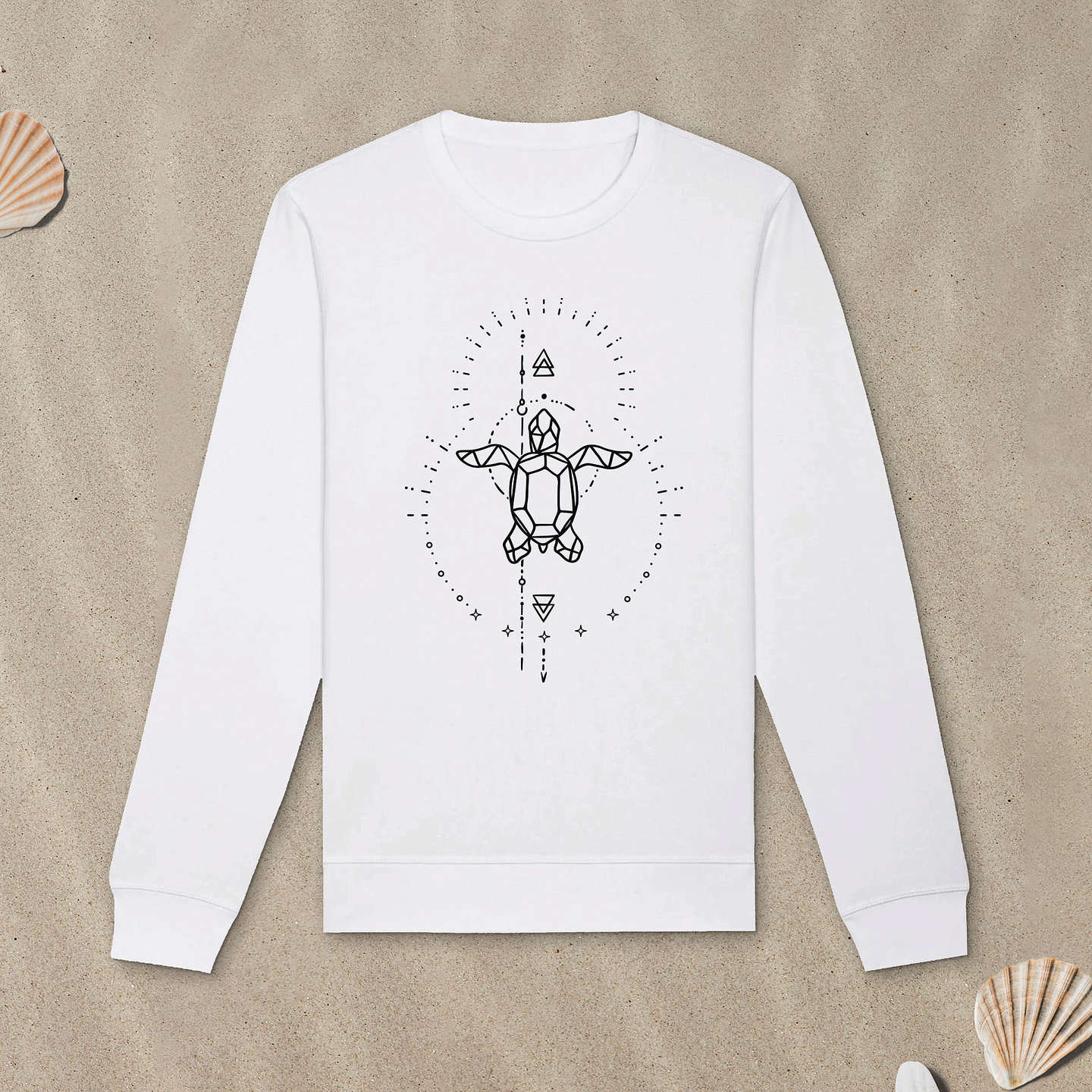 Weißes Sweatshirt mit Meeresschildkröte-Motiv mit Astrologie-Elementen liegt im Sand.