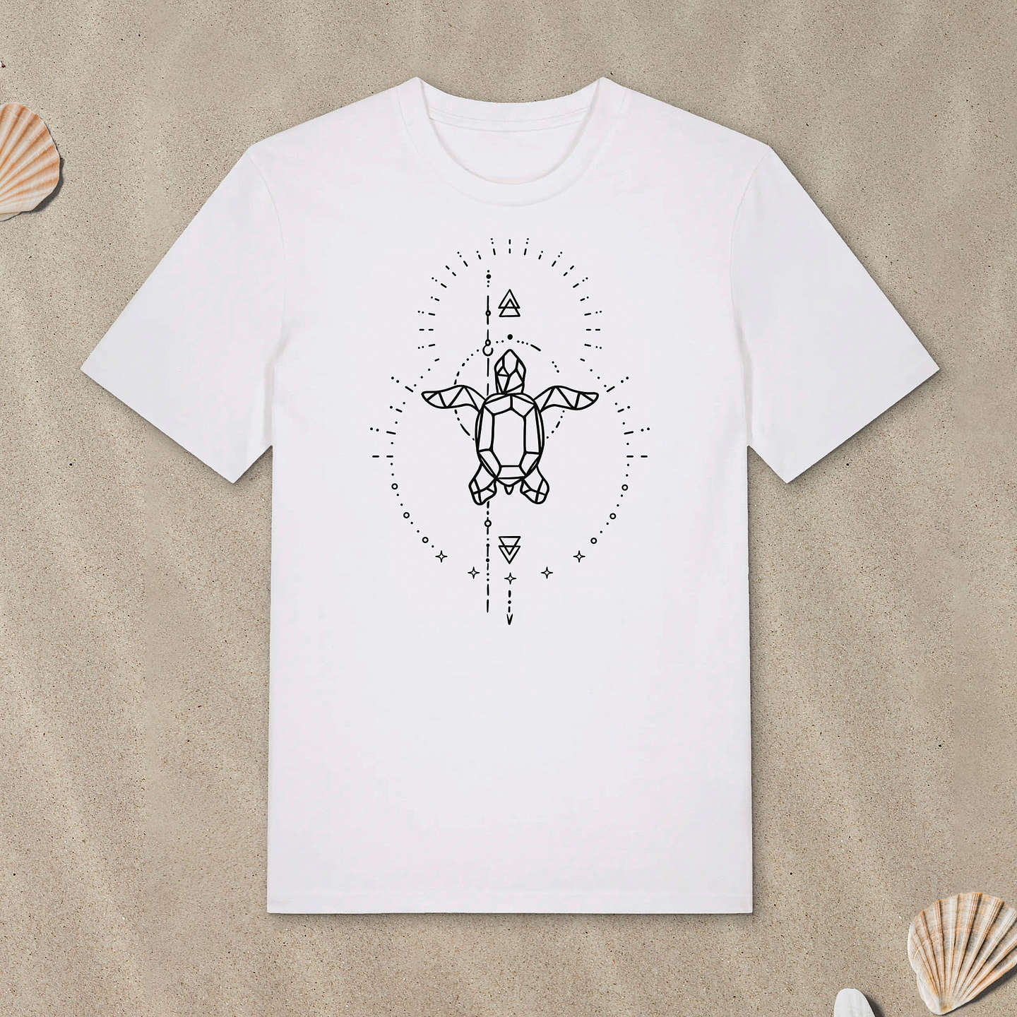 Weißes T-Shirt mit Meeresschildkröte-Motiv mit Astrologie-Elementen liegt im Sand.
