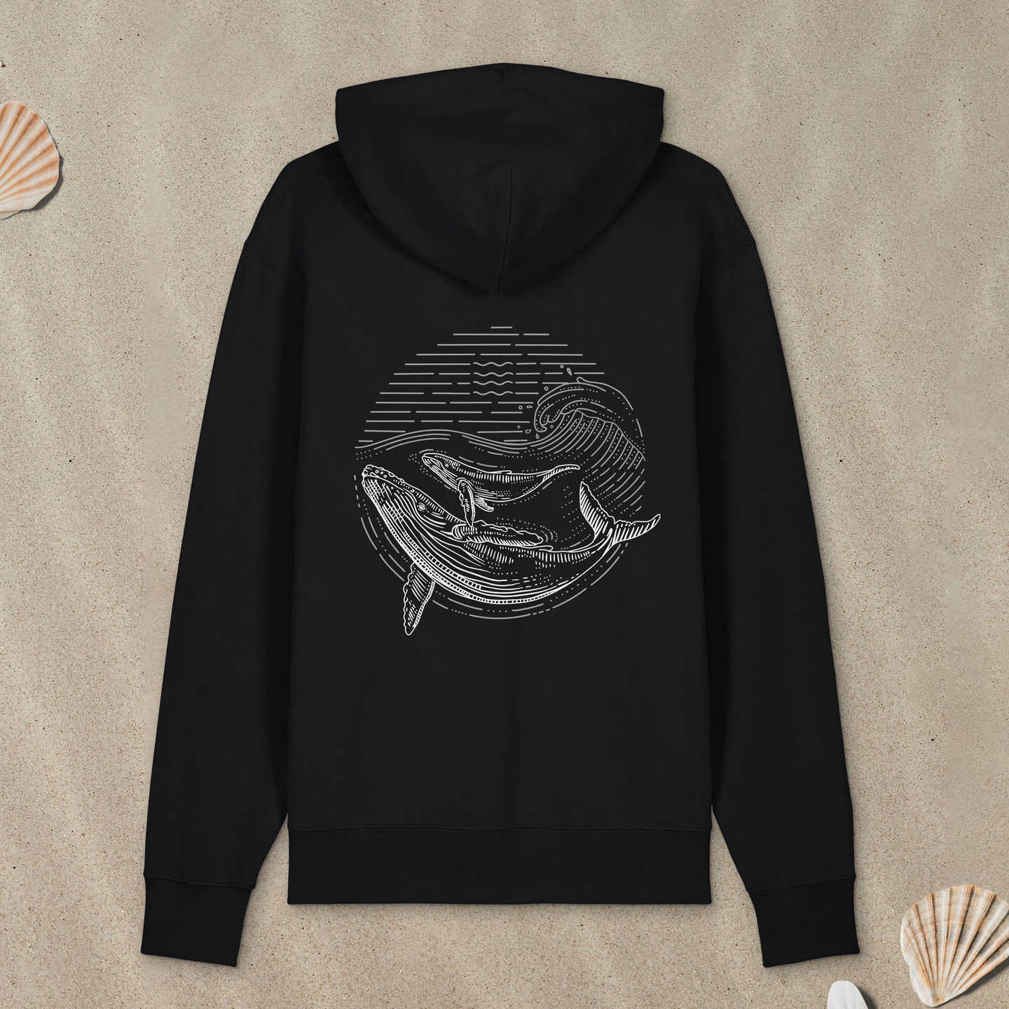 Schwarzer Hoodie mit Buckelwal-Motiv im Lineart-Stil liegt im Sand.
