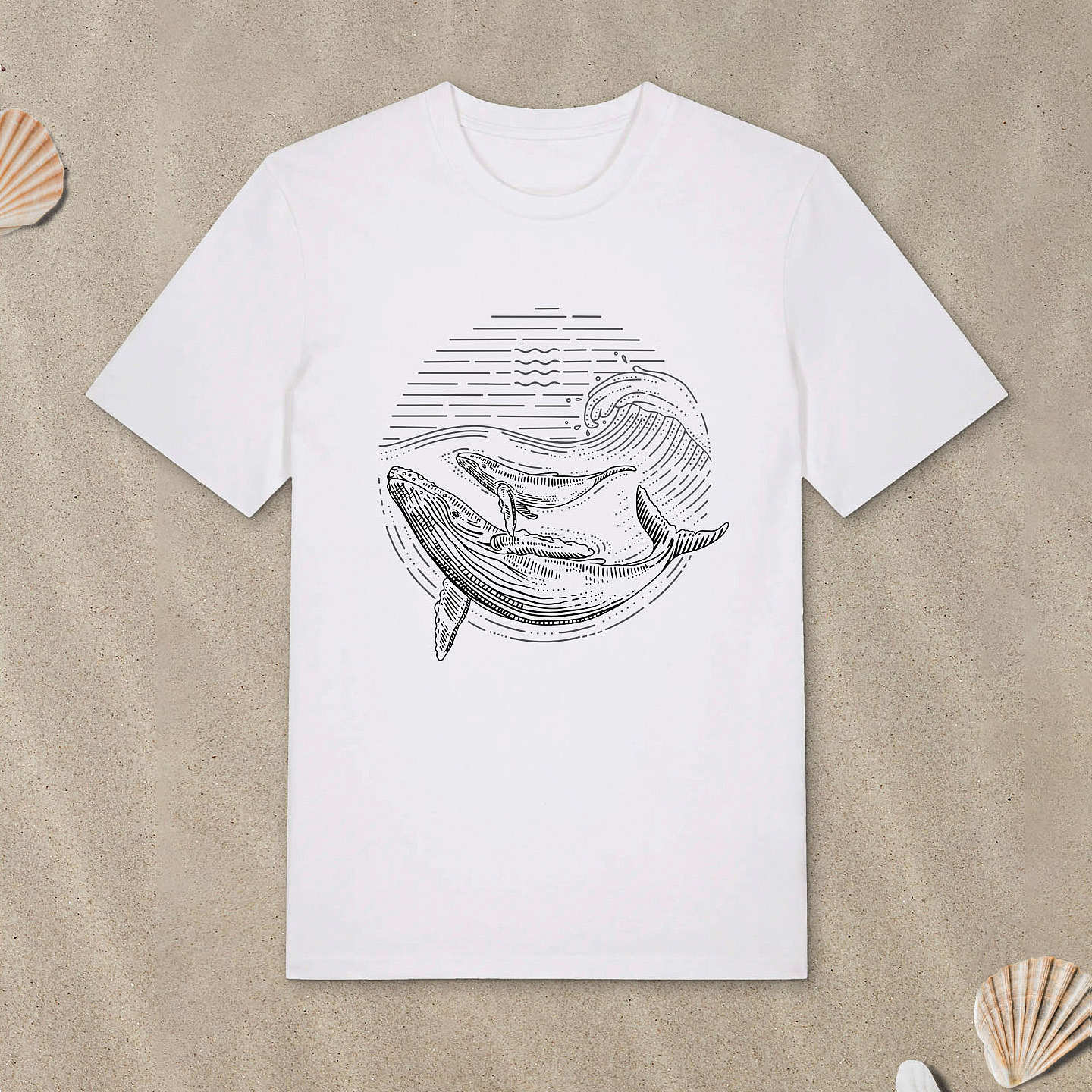 Weißes T-Shirt mit Buckelwal-Motiv im Lineart-Stil liegt im Sand.