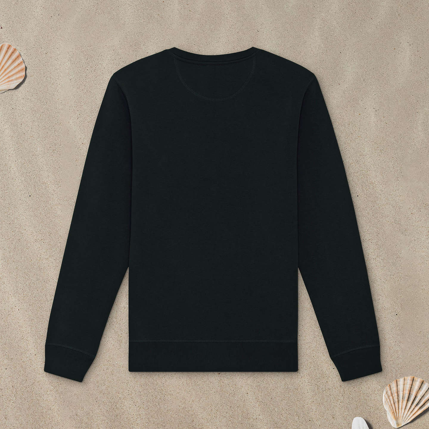 Schwarzes Sweatshirt liegt mit der Rückseite nach oben im Sand.