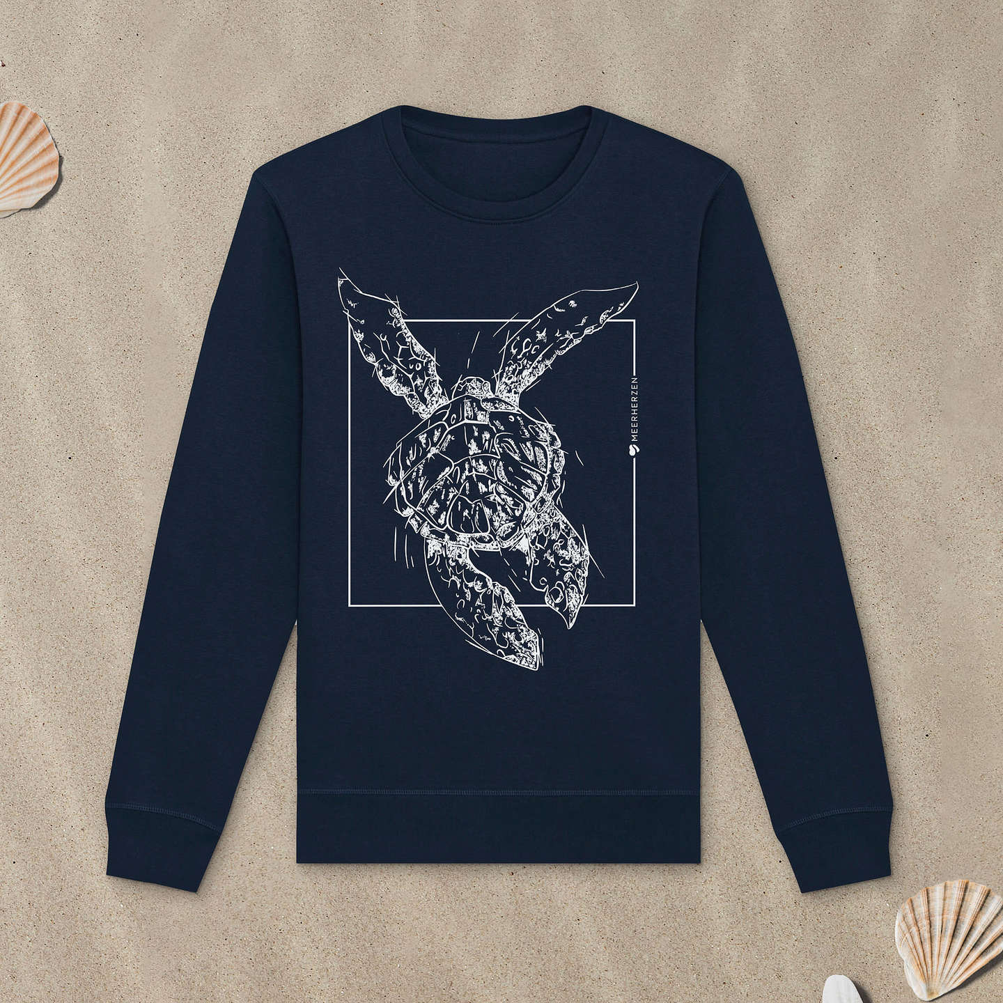 Marineblaues Sweatshirt mit Meeresschildkröte-Motiv liegt im Sand.