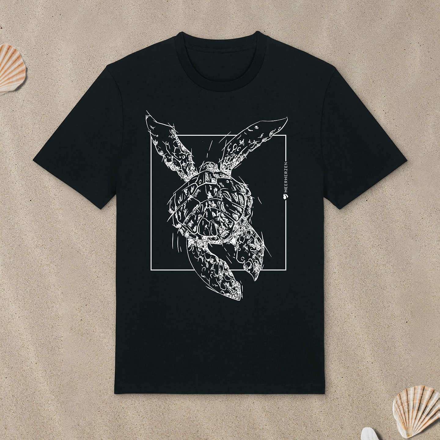 Schwarzes T-Shirt mit Meeresschildkröte-Motiv liegt im Sand.