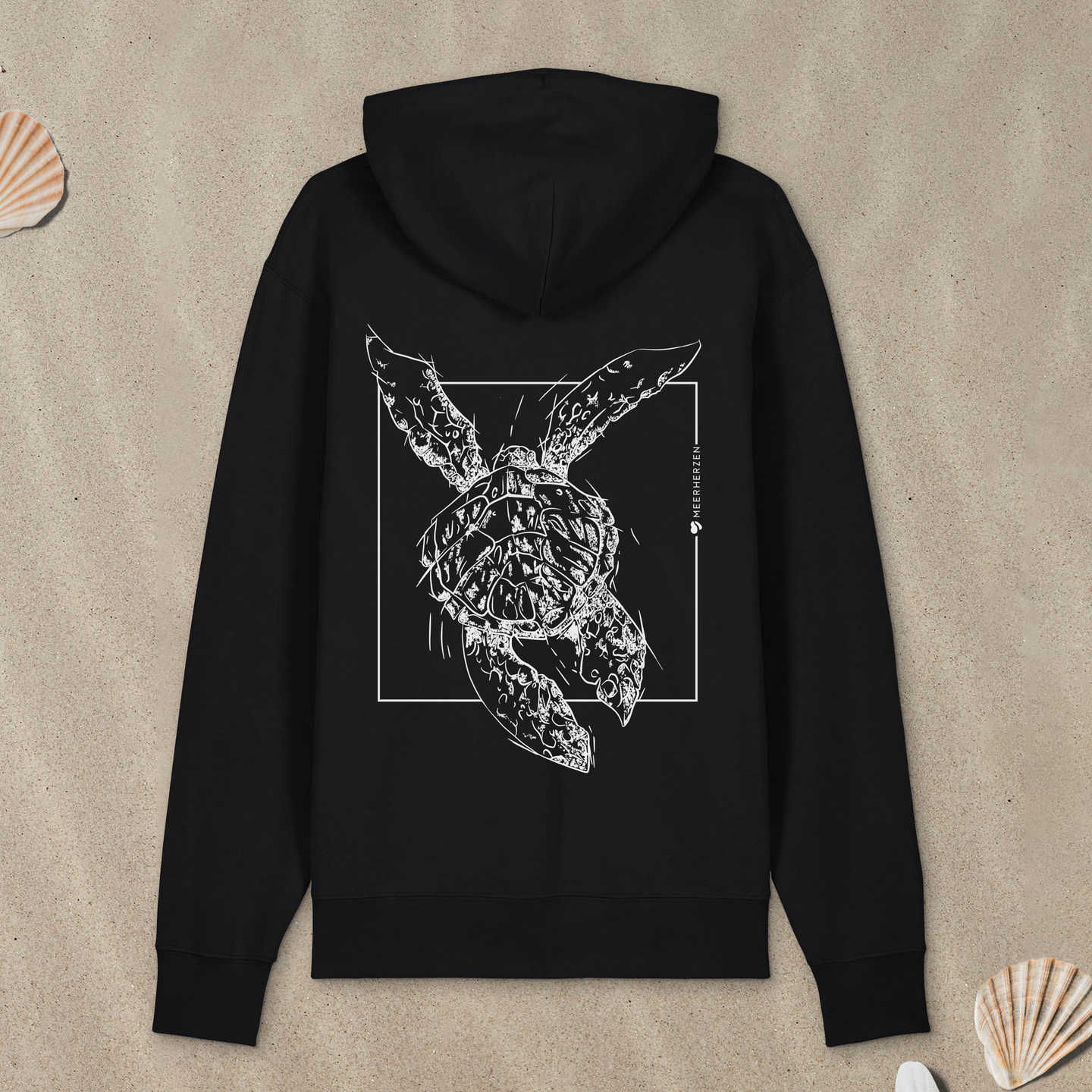 Schwarzer Hoodie Zipper mit Meeresschildkröte-Motiv mit Astrologie-Elementen liegt im Sand.