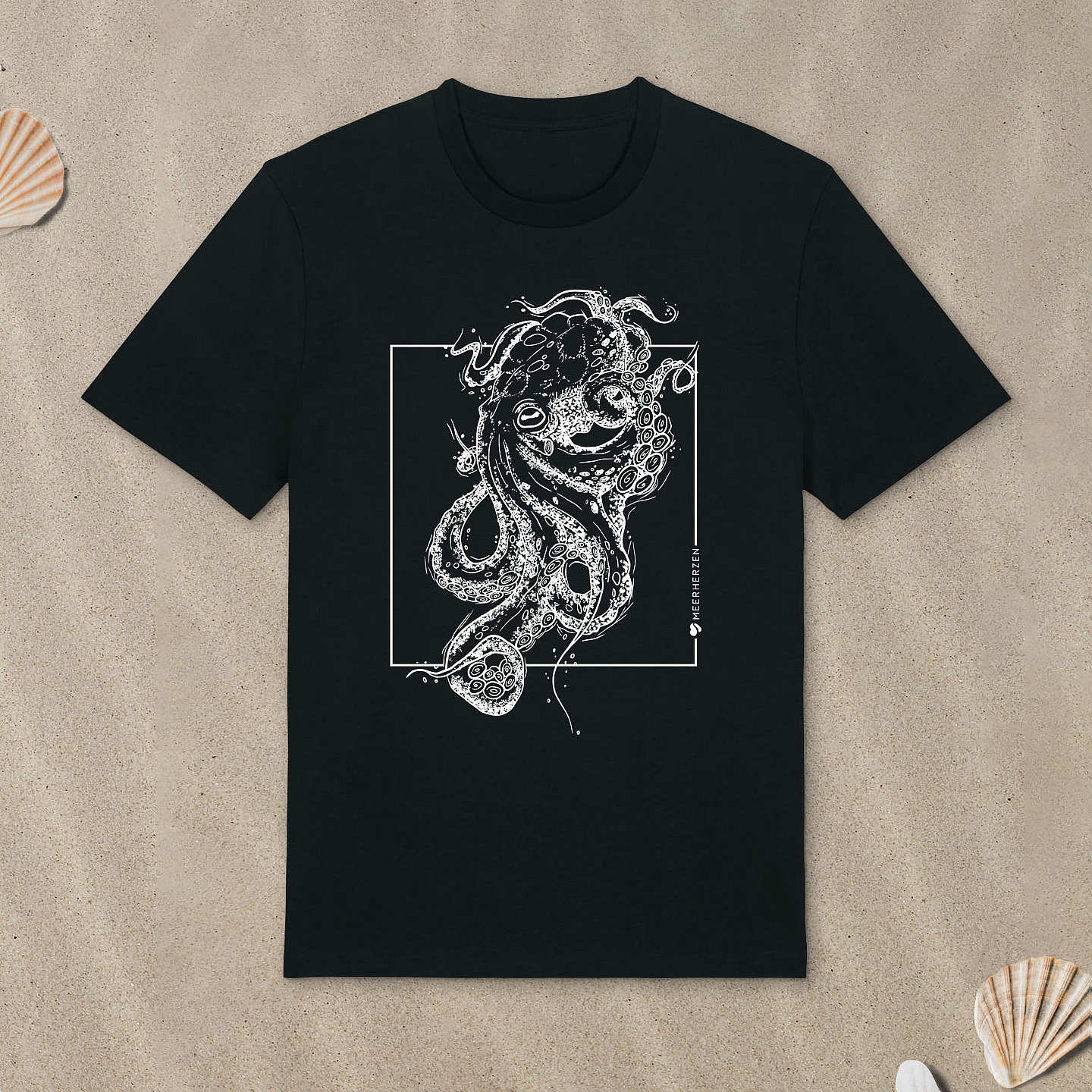 Schwarzes T-Shirt mit Tintenfisch-Motiv liegt im Sand.