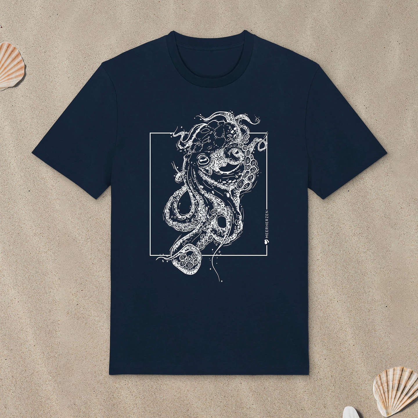 Marineblaues T-Shirt mit Tintenfisch-Motiv liegt im Sand.