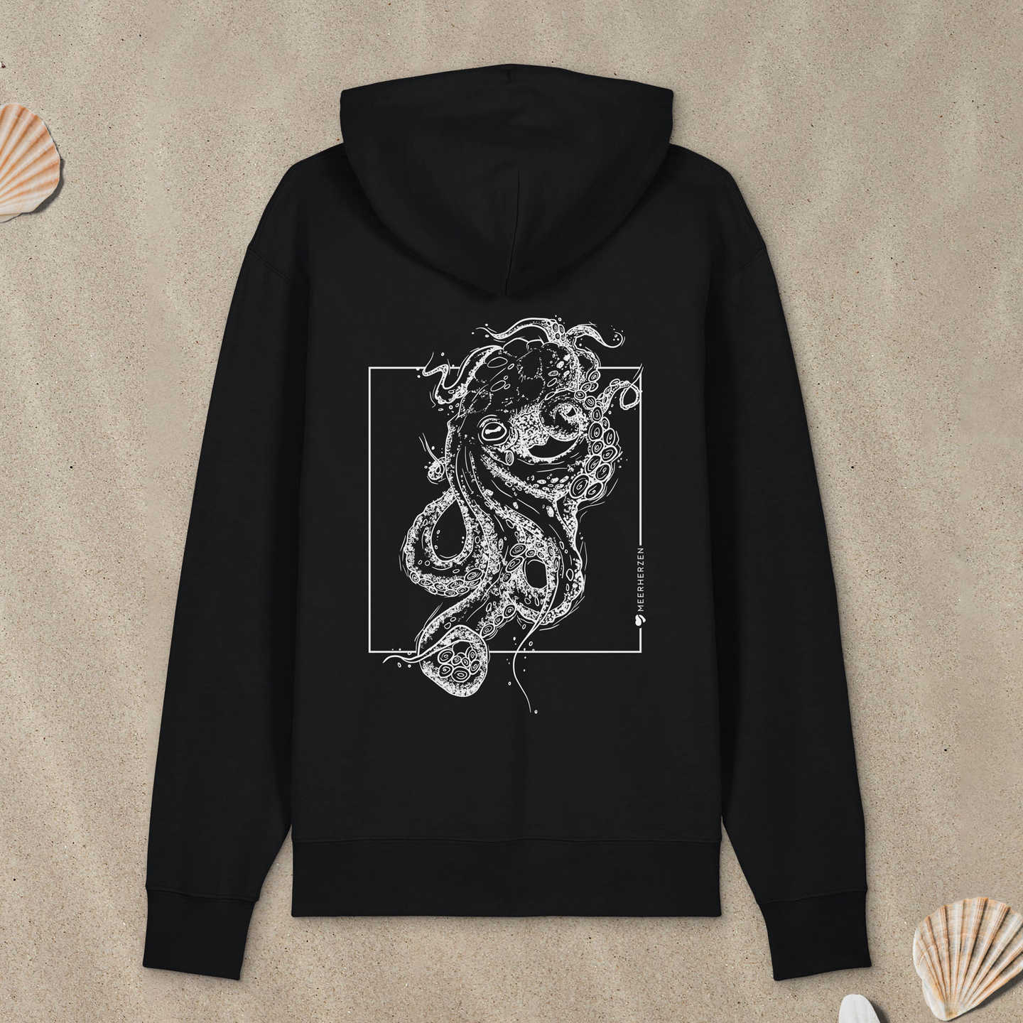 Schwarzer Hoodie Zipper mit Tintenfisch-Motiv liegt im Sand.