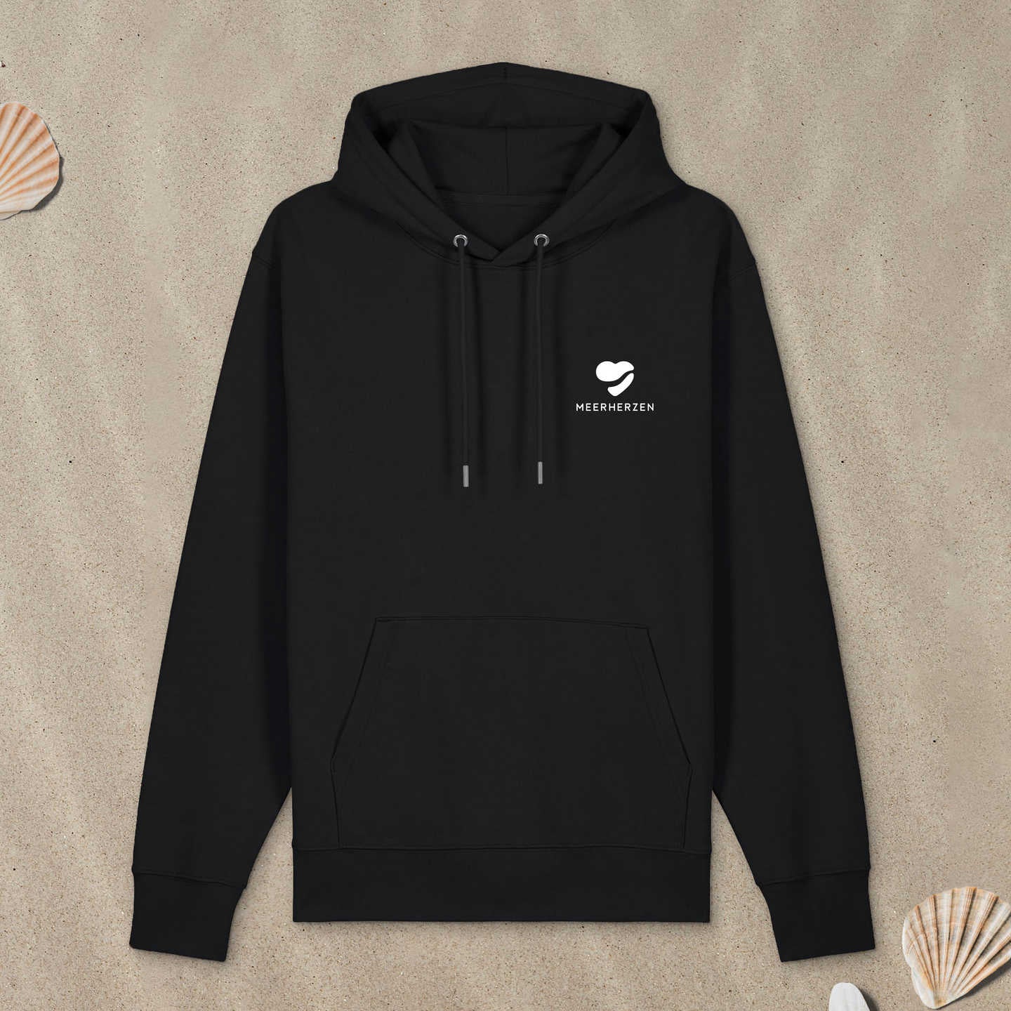 Schwarzer Hoodie mit Herz-Logo auf der Brust liegt im Sand.